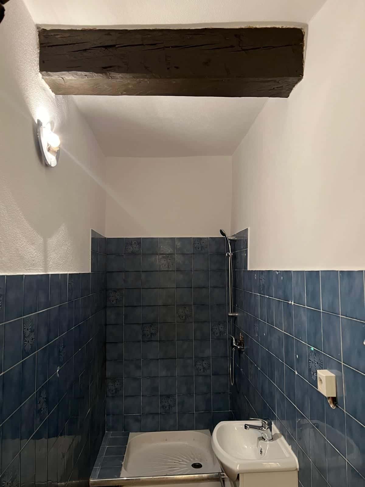 La même salle d’eau avec murs repeints et douche installée