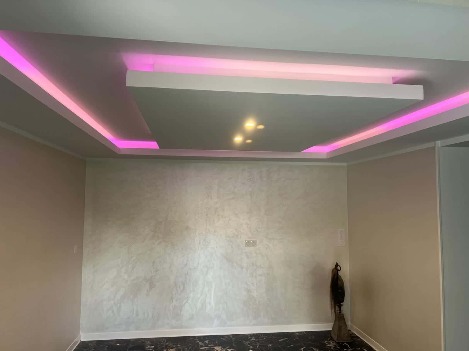 Plafond décoratif avec éclairage indirect rose dans une pièce rénovée
