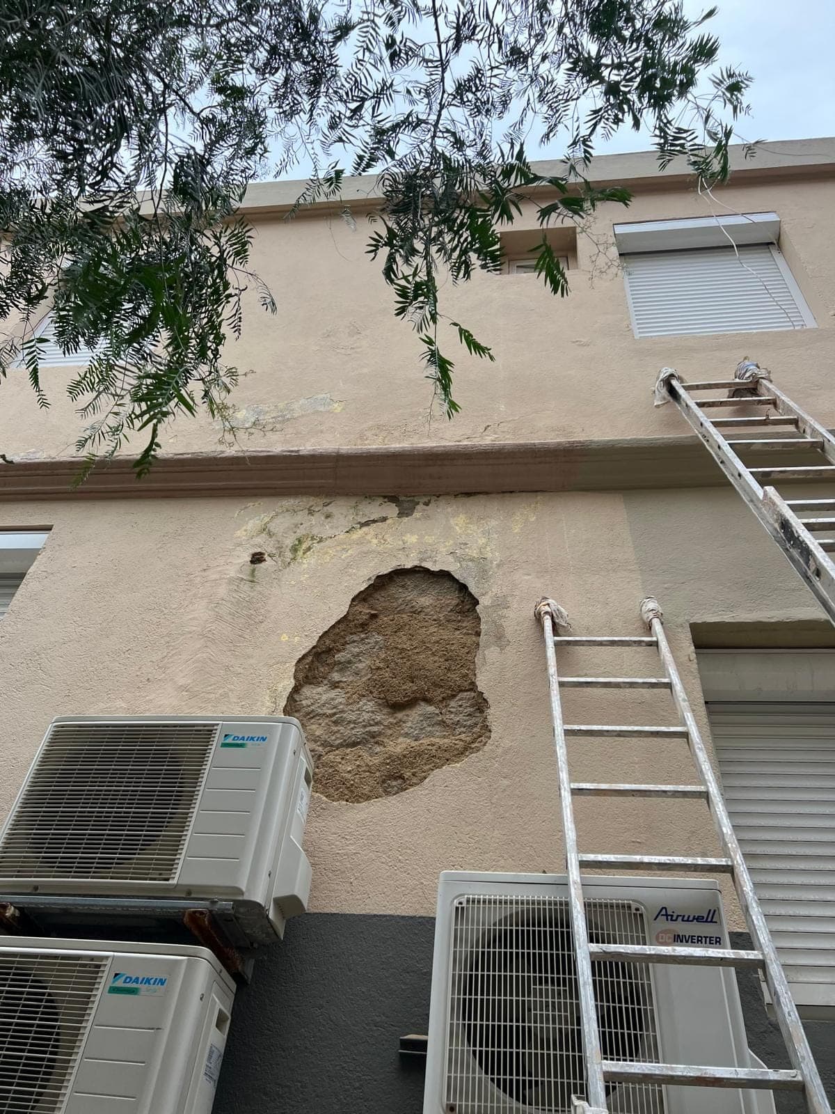 Façade avec enduit arraché près des climatiseurs