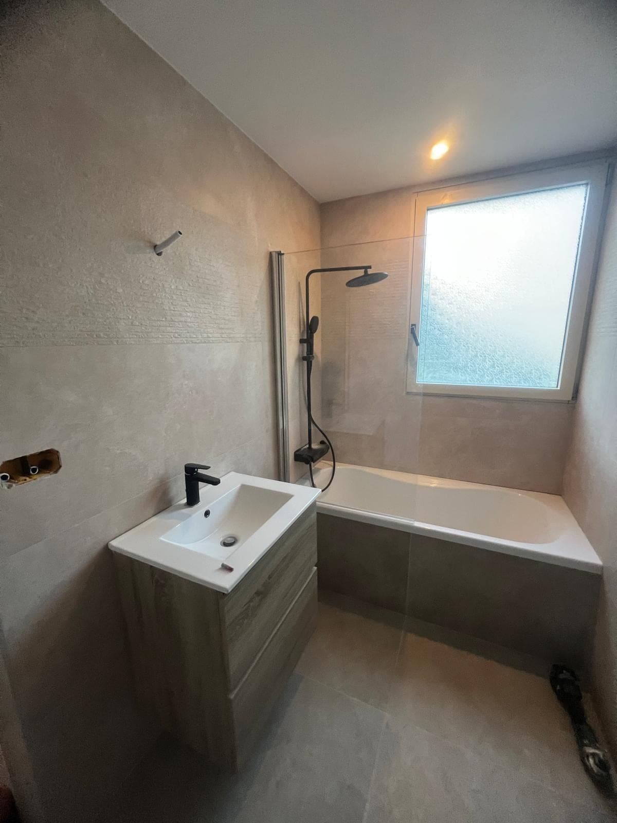 Salle de bain rénovée avec baignoire et meuble vasque